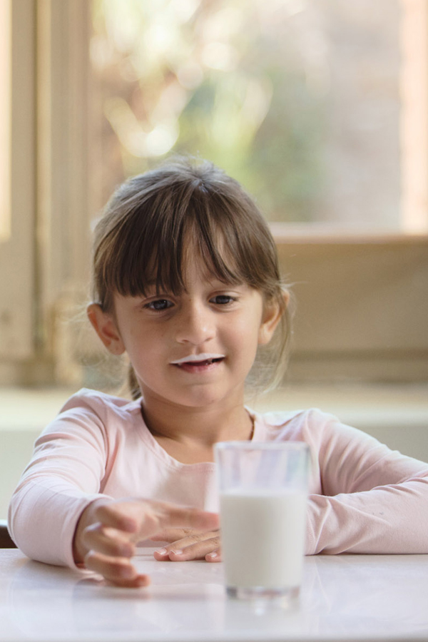 Una niña toma un vaso de leche